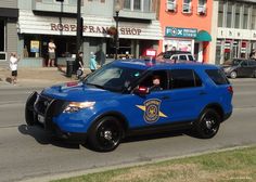 a police car is parked on the side of the road in front of some shops