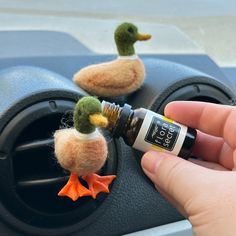 someone is holding an essential oil in their hand and there are two ducks on the dashboard