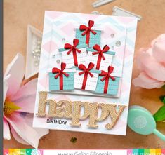 a happy birthday card with gift boxes on it and pink flowers in the foreground