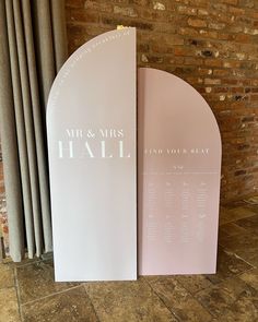 a couple of signs sitting on top of a floor next to a brick wall in front of a window