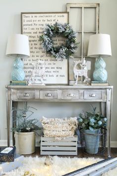 a table with two lamps and some plants on it in front of a framed sign