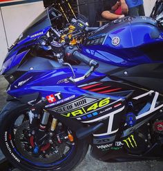 a blue motorcycle parked in front of a man standing next to it's bike