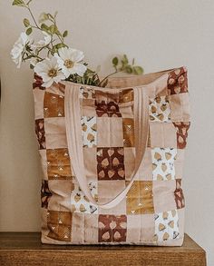 a purse sitting on top of a wooden table next to a vase with flowers in it