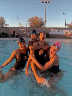 four people are in the water with their arms around each other and one person is wearing goggles