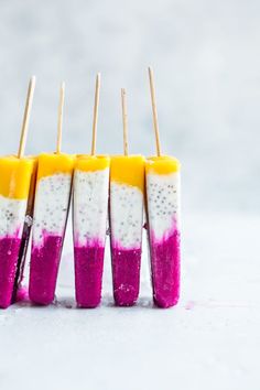 four popsicles with different colored toppings on sticks