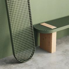 a green bench sitting next to a wall with a piece of wood sticking out of it