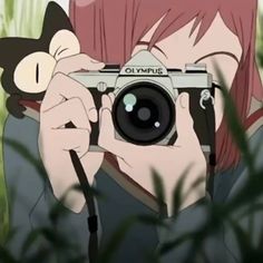 a person taking a photo with a camera in front of some tall grass and plants