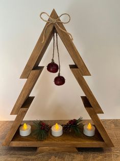 a wooden christmas tree with three candles in it