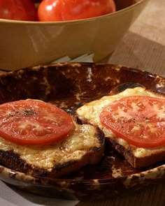 two slices of bread with tomatoes in the background and a bowl of tomatoes on the table