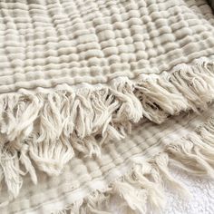 a white blanket with fringes laying on top of it