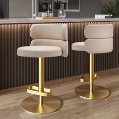 two white and gold bar stools sitting in front of a counter top with a plant on it