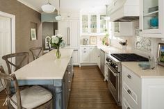 a kitchen with white cabinets and counter tops next to a dining room table in front of an oven