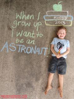 a young boy standing in front of chalk writing on the ground with an apple and plant