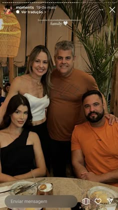 four people are posing for a photo at a table with food and drinks on it