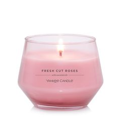 a pink candle sitting in front of a white background with the words fresh cut roses on it