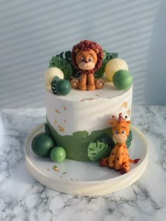 a white cake topped with a lion and giraffe figurines