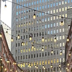 the lights are hanging from the wires on the building's sides as people walk down the street