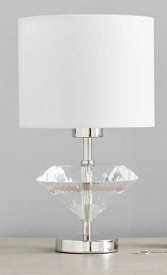 a glass table lamp with a white shade on the base and a silver plate underneath it