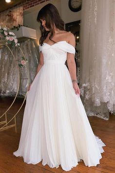 a woman in a white dress standing on a wooden floor