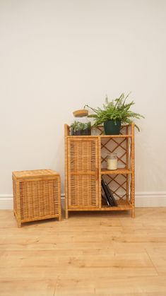 two wicker shelves with plants and books on them in front of a white wall