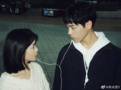 a young man and woman standing next to each other with ear buds in their ears