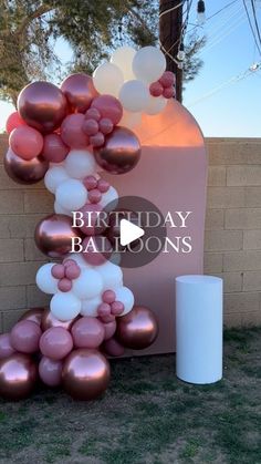 a bunch of balloons that are on the ground in front of a sign with words birthday balloons