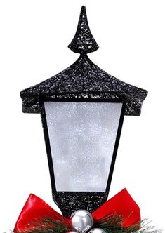 a street light with a red bow and christmas decorations on it's front side