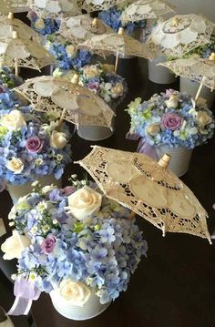 several vases filled with flowers and umbrellas on top of a black table covered in lace