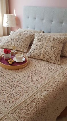 a bed topped with pillows and a tray filled with food