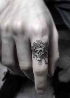 a person with a skull tattoo on their finger