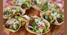 some tacos are sitting on a wooden platter with other food items in it