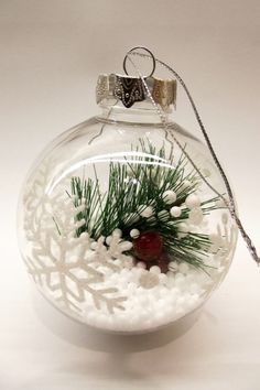 a glass ornament filled with snow and pine needles