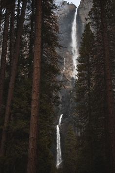 a waterfall is seen through the trees on a cloudy day in yosemite national park, california