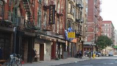 people are walking down the street in front of tall buildings with fire escapes on them