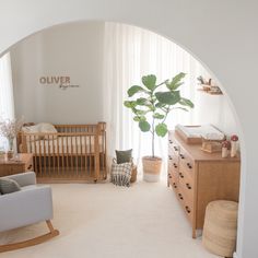 a baby's room with a crib, rocking chair, dresser and large potted plant