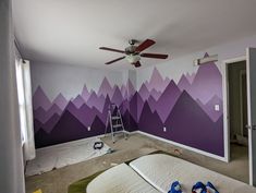 a room with purple mountains painted on the wall and a ladder in the corner next to it