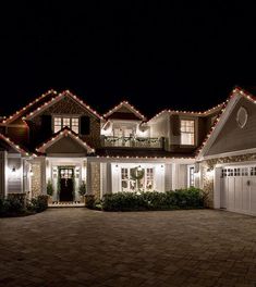 a large house with christmas lights on the roof and garage doors in front of it