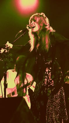 a woman singing into a microphone on stage