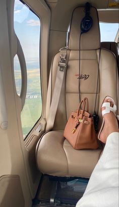 a woman's feet in the back seat of an airplane with her handbag