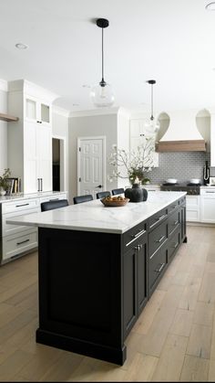 a large kitchen with white cabinets and black island