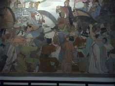 a large painting on the side of a building with people standing around and riding horses