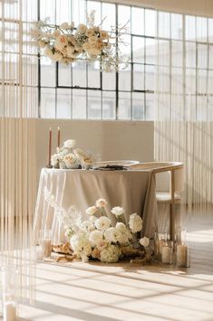 a table with flowers and candles on it in the middle of a room filled with sheer curtains