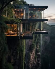 two glass houses on the edge of a cliff overlooking a waterfall at night with lights on