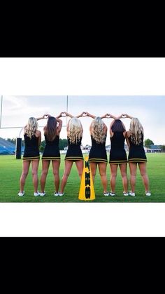 four girls in black dresses are holding their hands together and standing on the field with yellow cones