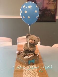 a teddy bear sitting in a box with a blue balloon attached to it's head