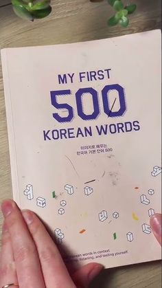 a person holding up a book with korean words on it