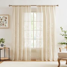 a living room with white curtains and a chair in front of a window that is open to the outside