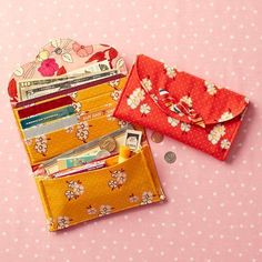 two small wallets sitting next to each other on a pink surface with polka dots