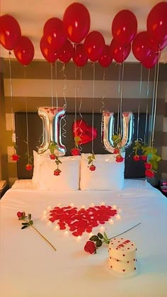 the bed is decorated with red balloons and white sheets, which spell out i love you