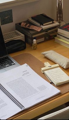 an open laptop computer sitting on top of a desk next to a pile of books